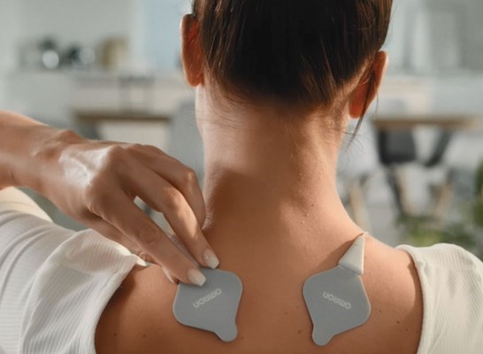 Woman using heat tens on back of shoulder